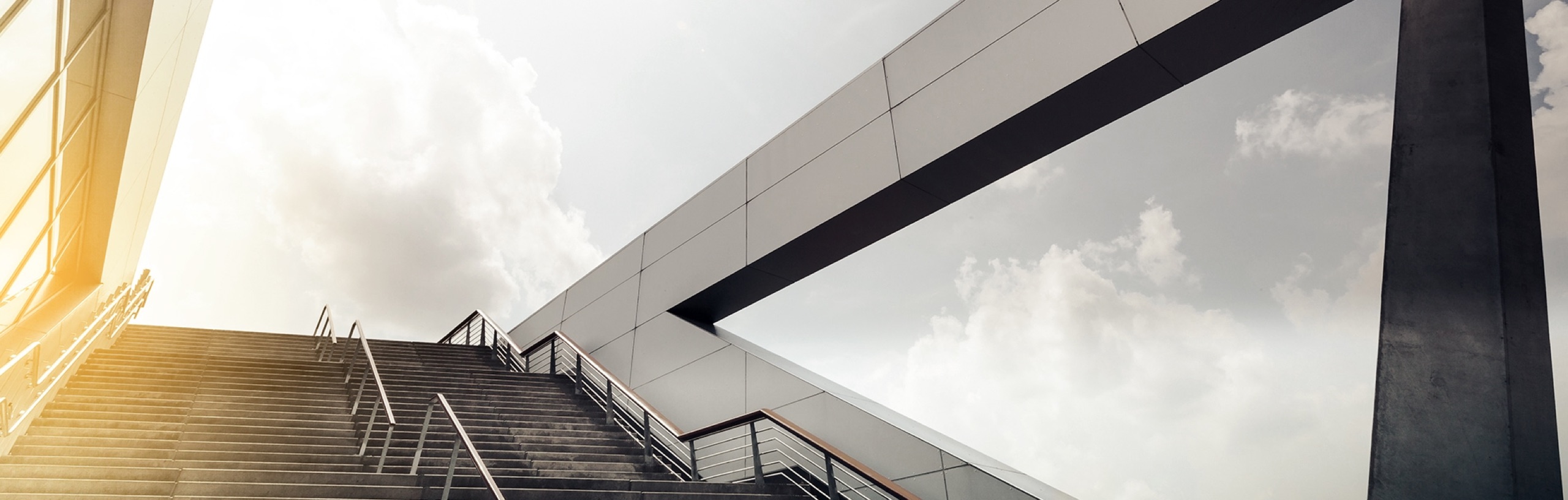 Treppe und moderne Gebäudefassade aus der Untersicht vor hellem Himmel