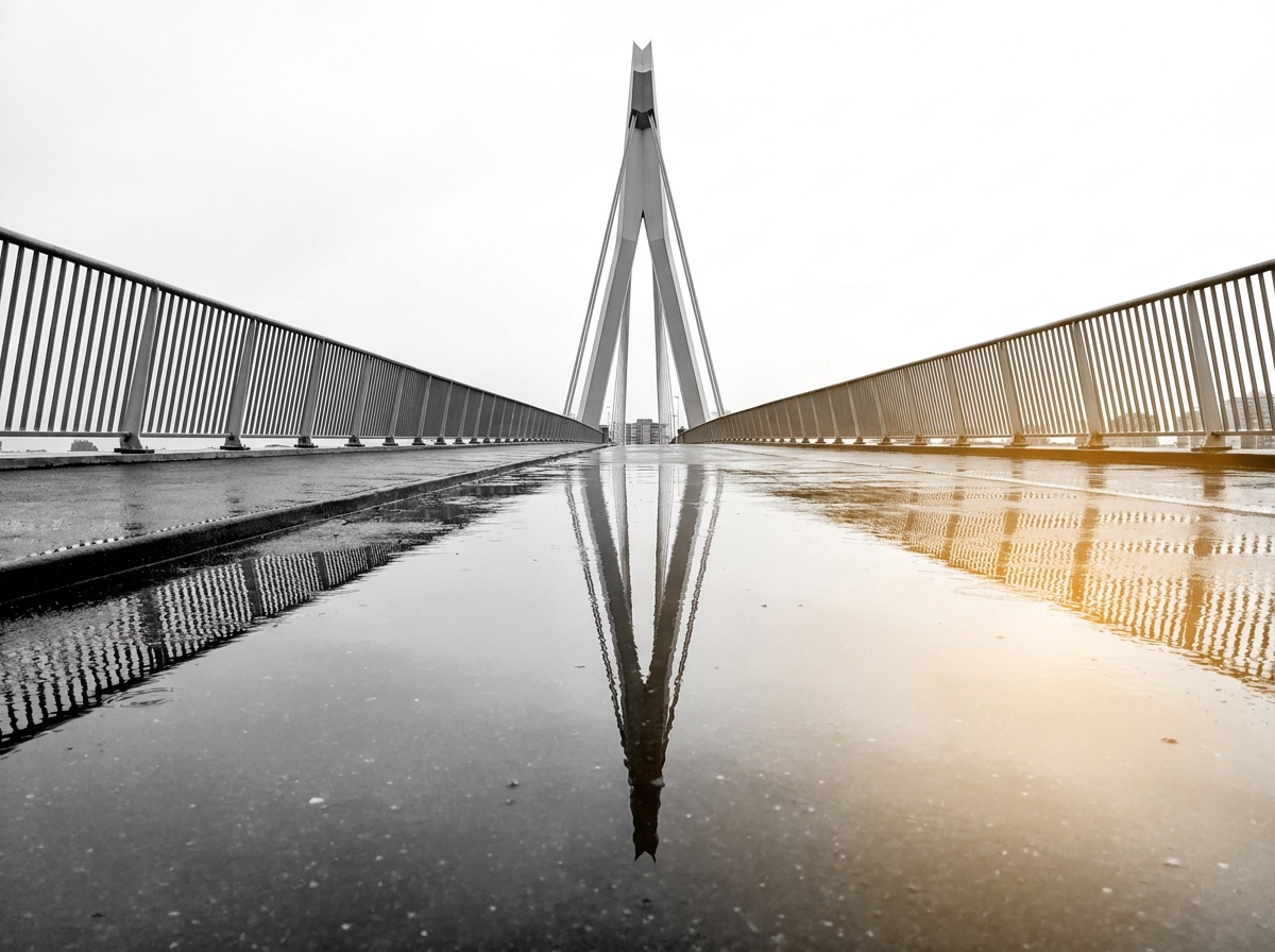 Bridge pylon reflected in a puddle on the walkway